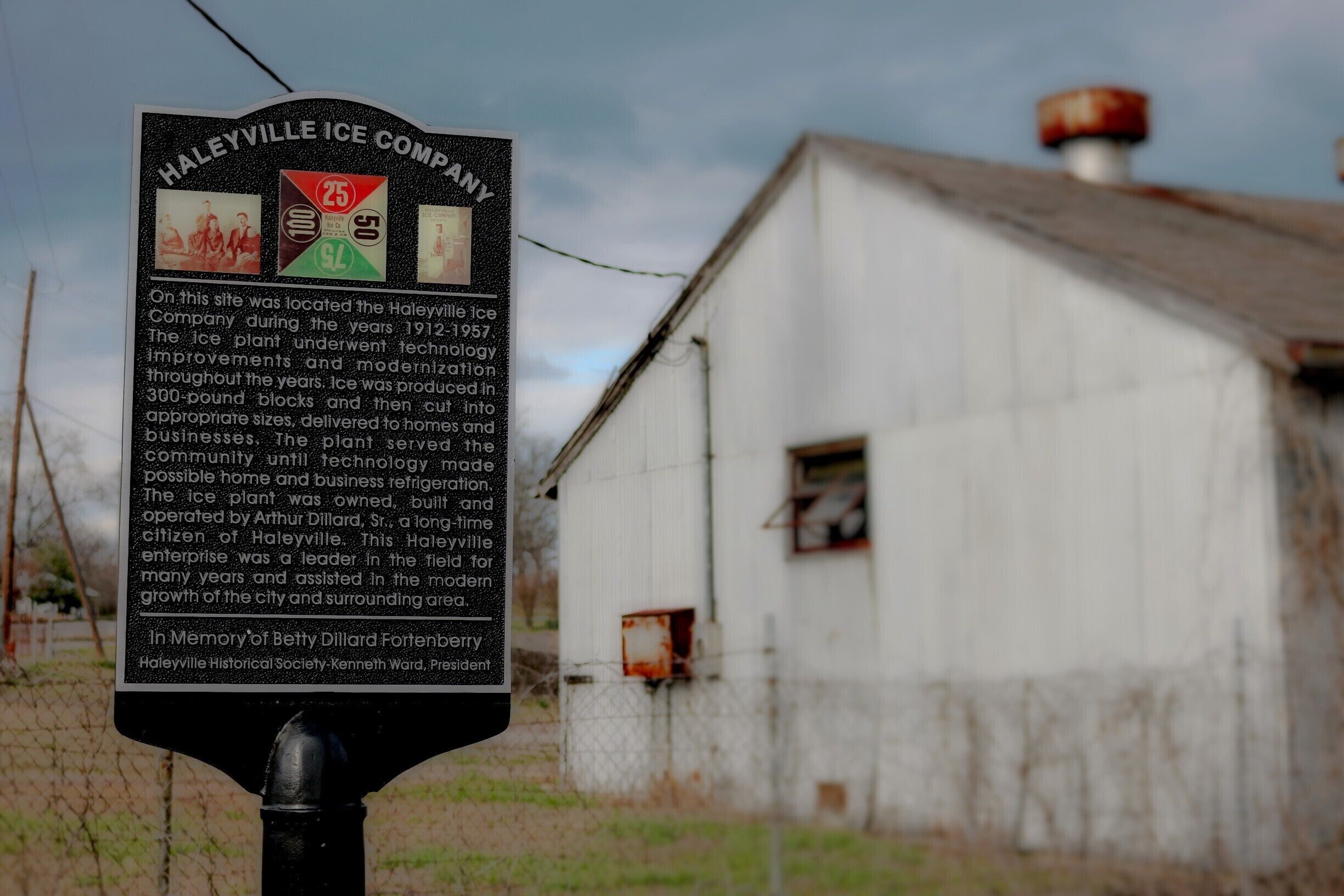A historical signboard with information about the Haileyville Ice Company, located in front of an old, weathered building.