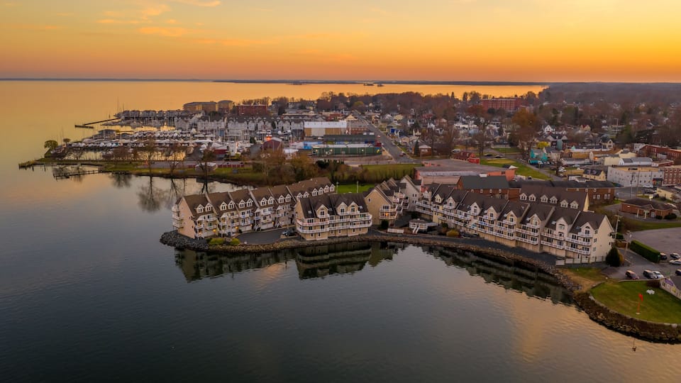Aerial view of downtown Havre de Grace in Maryland with luxury waterfront apartment complex reflecting in the water as the sun paints the sky orange