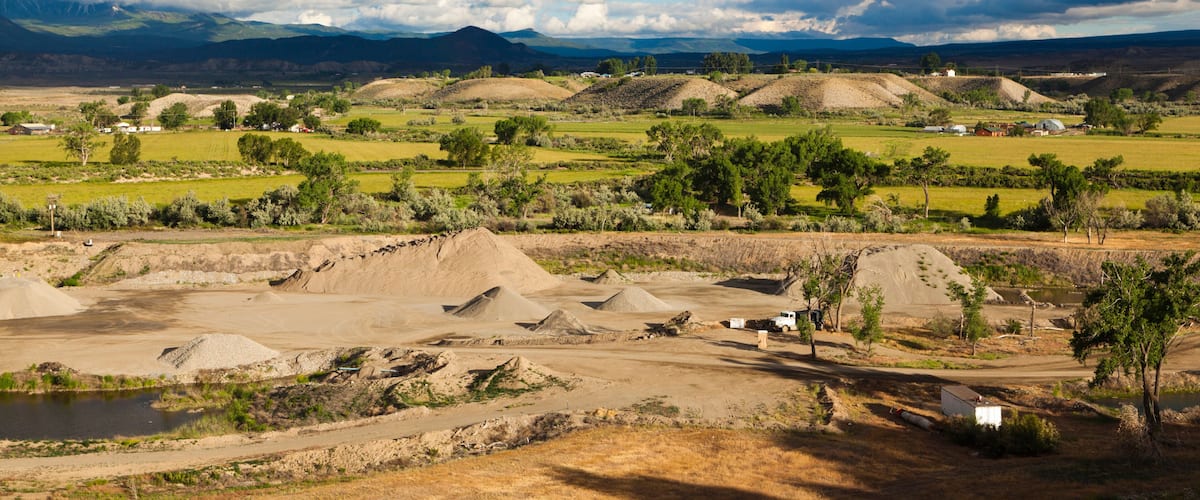 A rural landscape with rolling hills, a dirt road, and scattered buildings.