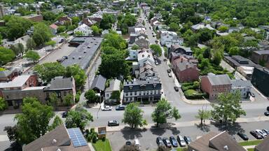aerial view of hudson, new york (small hudson valley town city downtown historic district) mountains catskills ny travel destination main street with hills clouds cars tree matter