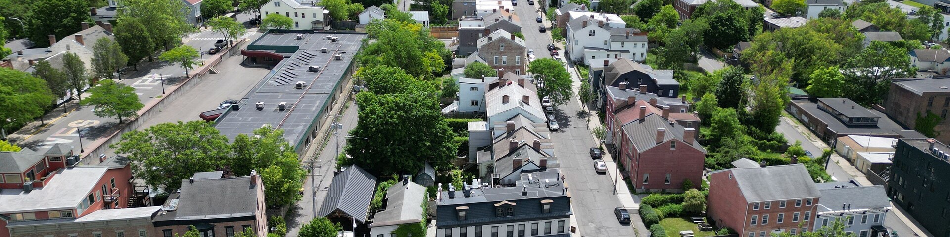 aerial view of hudson, new york (small hudson valley town city downtown historic district) mountains catskills ny travel destination main street with hills clouds cars tree matter