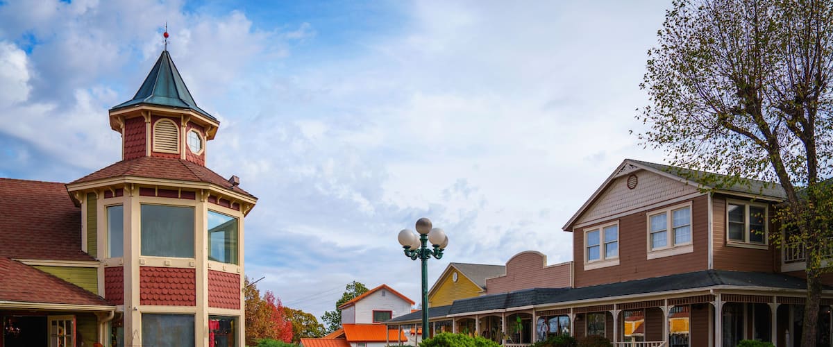 A quaint town square with a distinctive tower, a street lamp, and traditional houses.