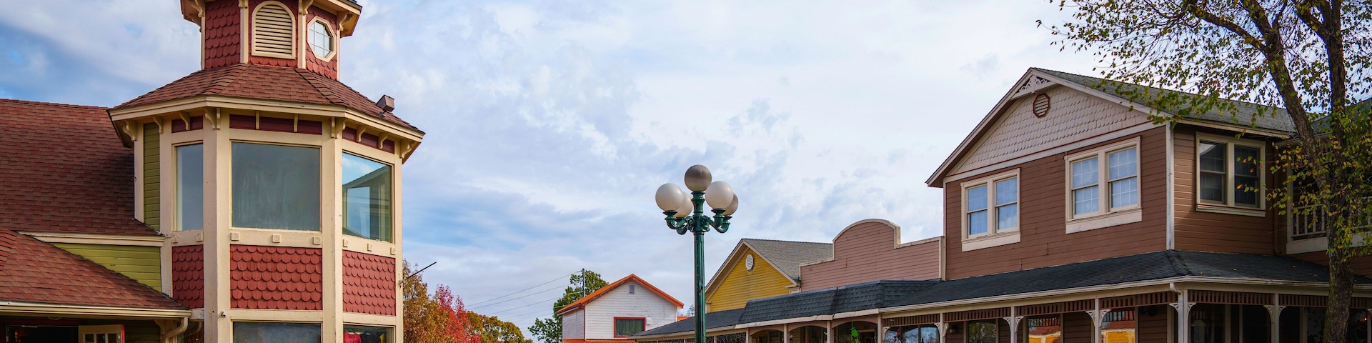A quaint town square with a distinctive tower, a street lamp, and traditional houses.