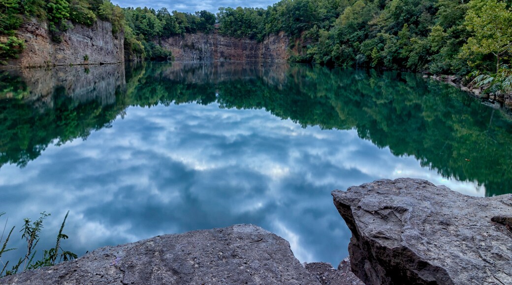 A calm lake reflecting the surrounding cliffs and dense forest.