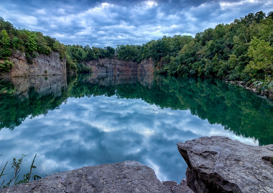 A calm lake reflecting the surrounding cliffs and dense forest.