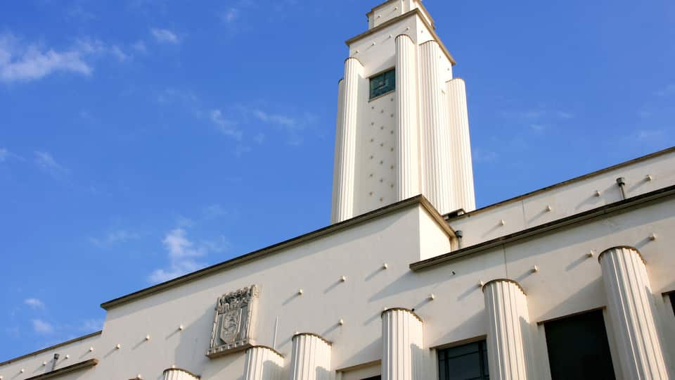 A building with white columns and a tower against a clear blue sky.