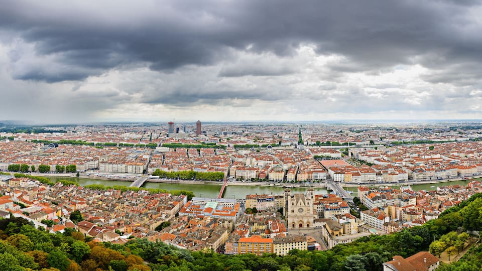 A panoramic view of a city with a river, historic buildings, and a prominent tower.