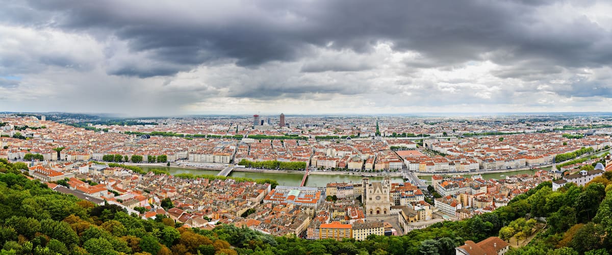A panoramic view of a city with a river, historic buildings, and a prominent tower.