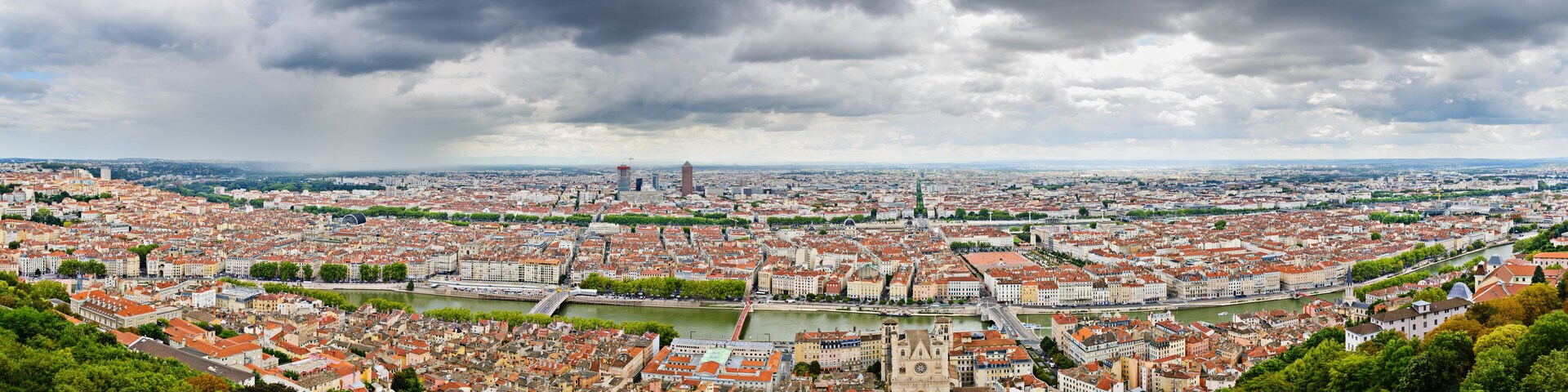 A panoramic view of a city with a river, historic buildings, and a prominent tower.