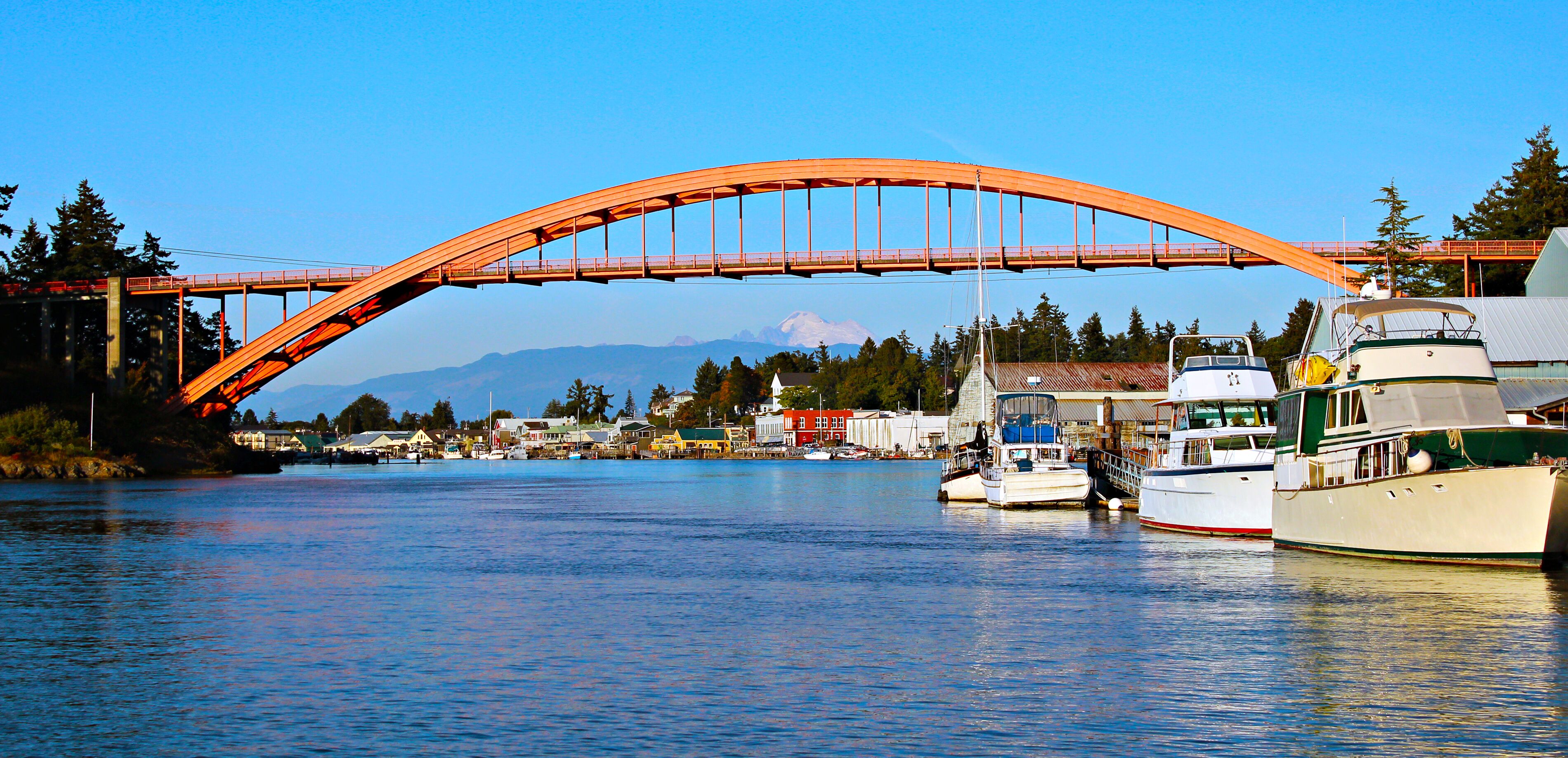 A river with boats, a bridge, and a mountain in the background.
