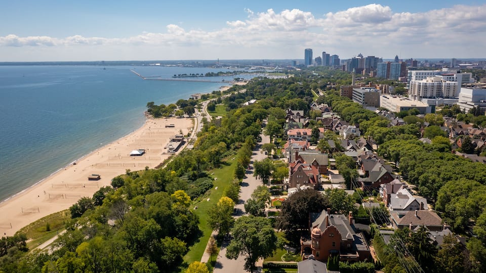 A coastal cityscape with a beach, dense greenery, and a prominent skyline.