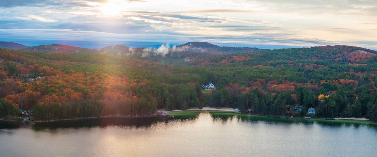 A lake surrounded by autumn-colored trees and hills.