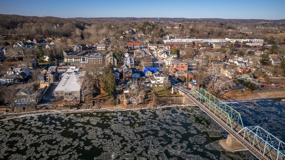 An aerial view of a town with a river, ice floes, and a bridge.