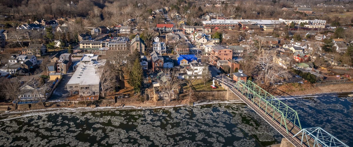 An aerial view of a town with a river, ice floes, and a bridge.
