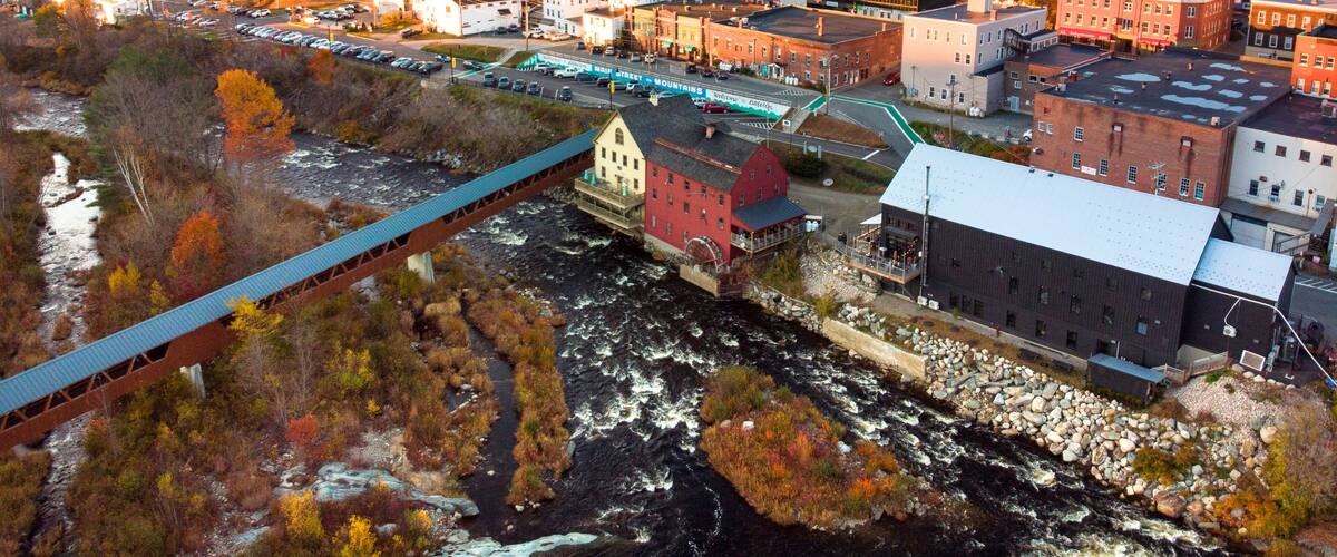 A town with a river, a bridge, and autumn-colored trees.
