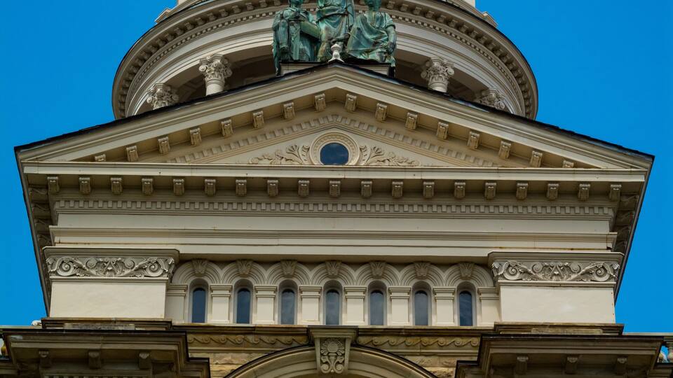 A grand building with a large dome and a clock, featuring classical architecture and statues.