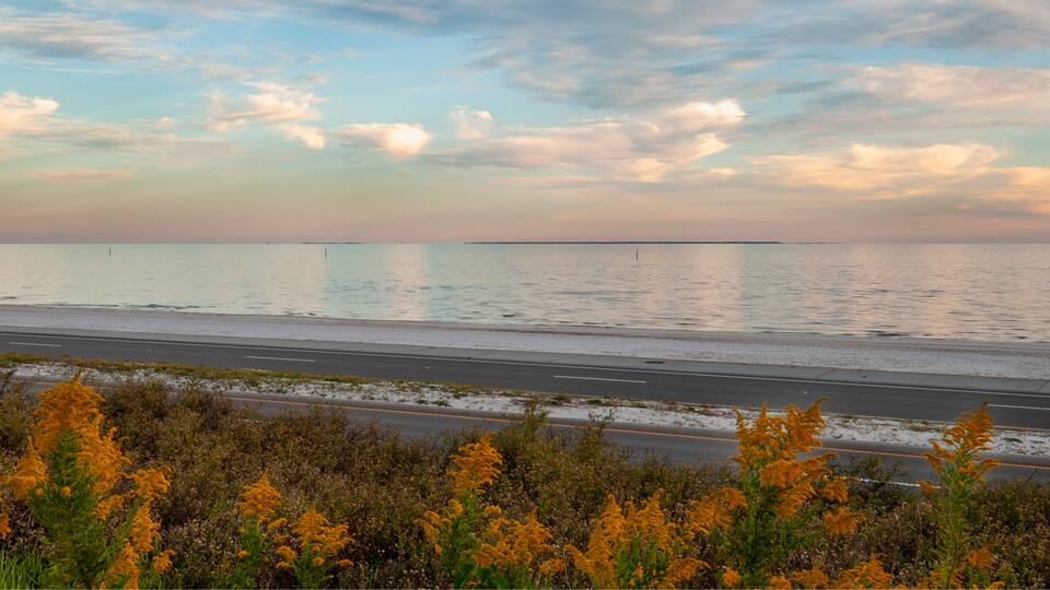 A coastal road with a clear sky and distant landmass.