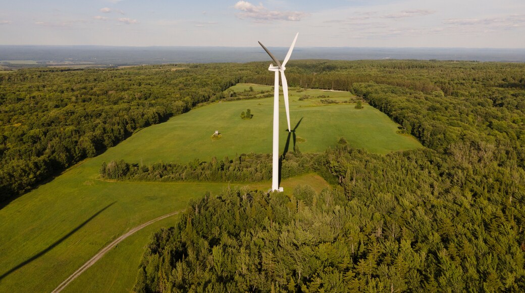 Aerial view of wind turbines in a scenic rural landscape with fields and forests under a cloudy sky, Lowville, United States of America.