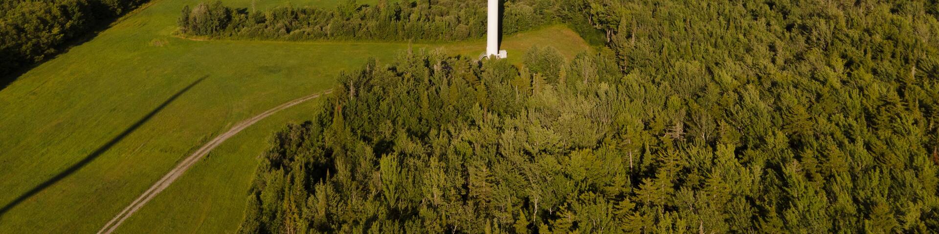Aerial view of wind turbines in a scenic rural landscape with fields and forests under a cloudy sky, Lowville, United States of America.