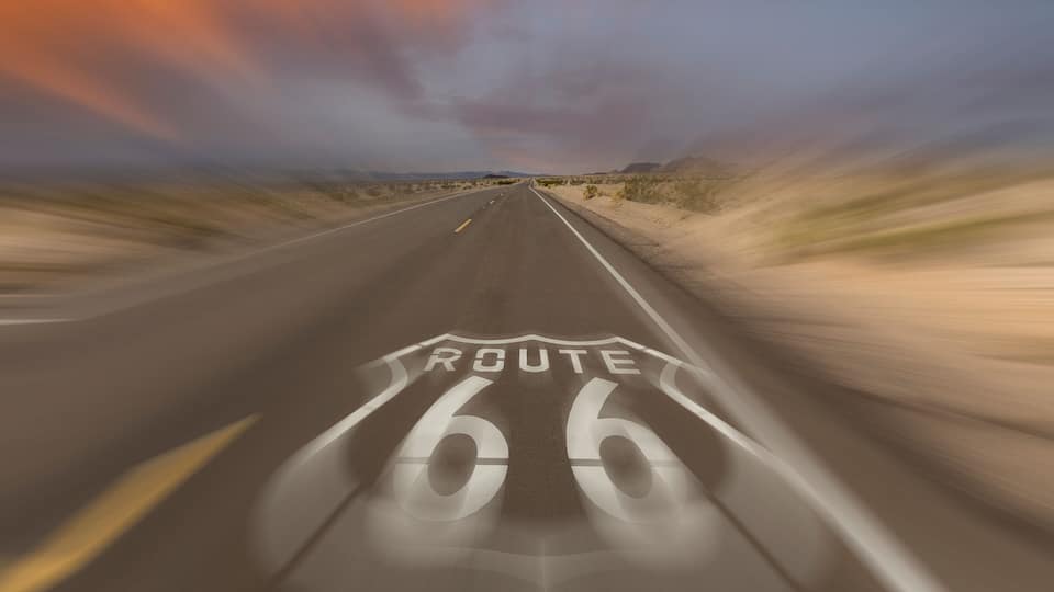 A road with Route 66 markings, surrounded by desert landscape.