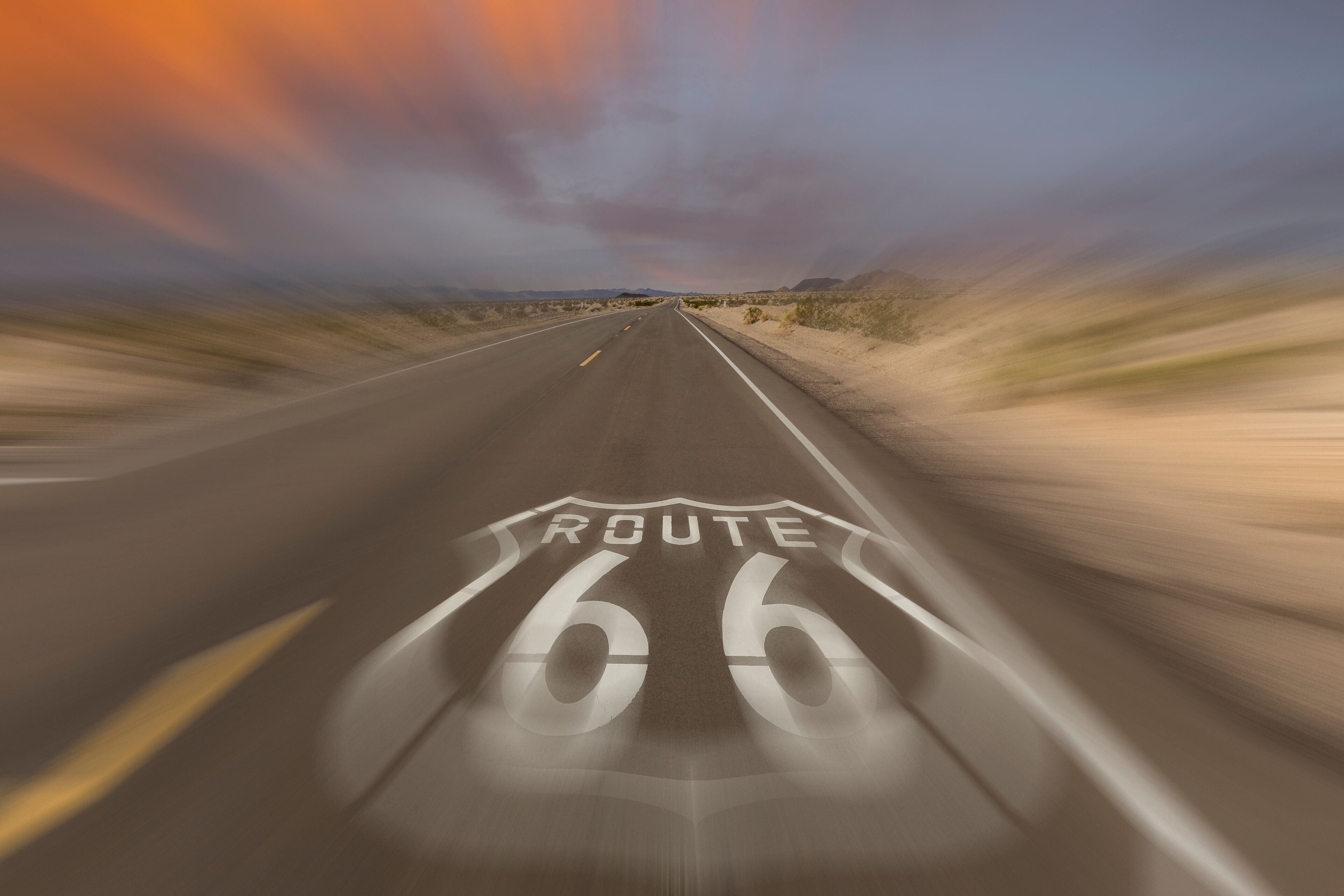 A road with Route 66 markings, surrounded by desert landscape.