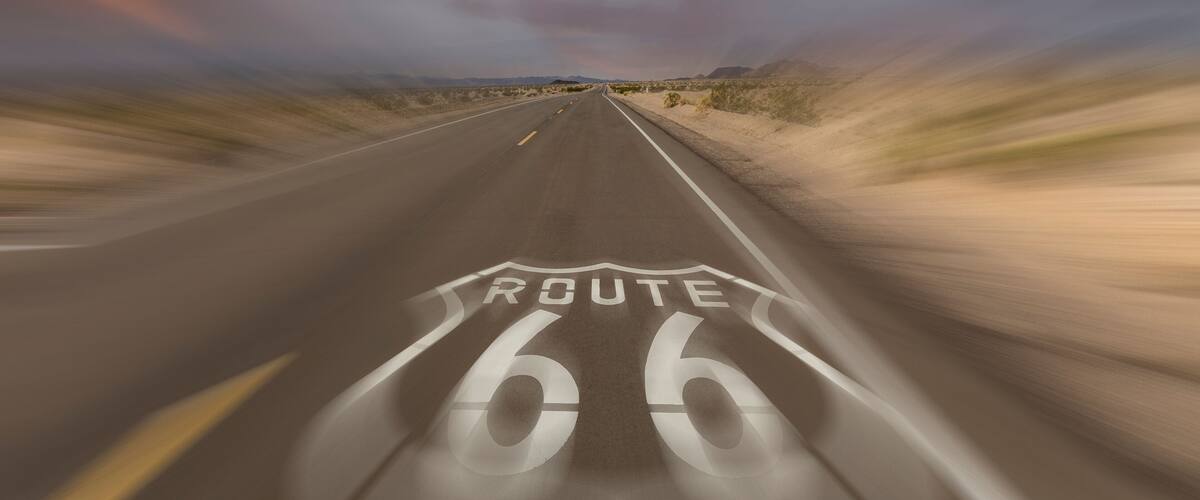 A road with Route 66 markings, surrounded by desert landscape.