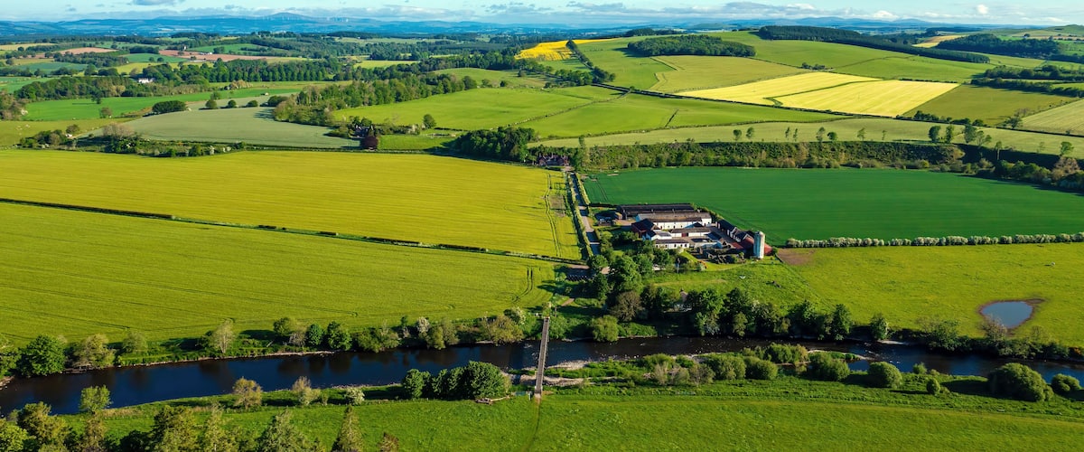 A rural landscape with fields, a river, and a farmstead.