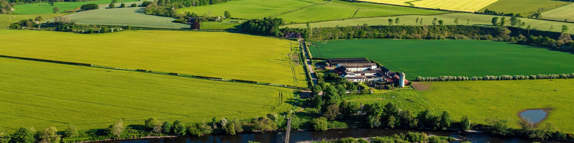 A rural landscape with fields, a river, and a farmstead.