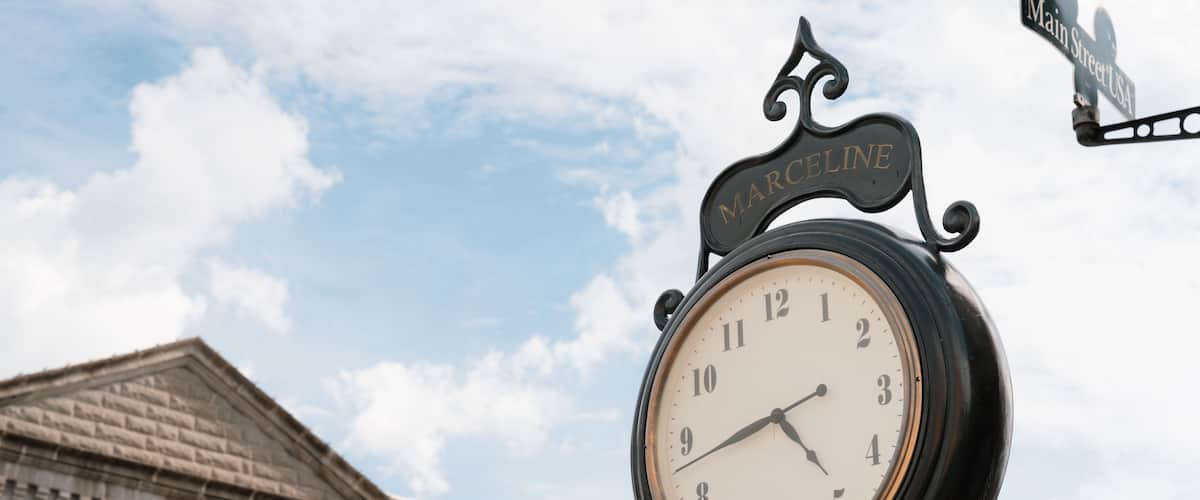 A clock with a sign reading 'Main Street USA' and a building with a brick facade in the background.