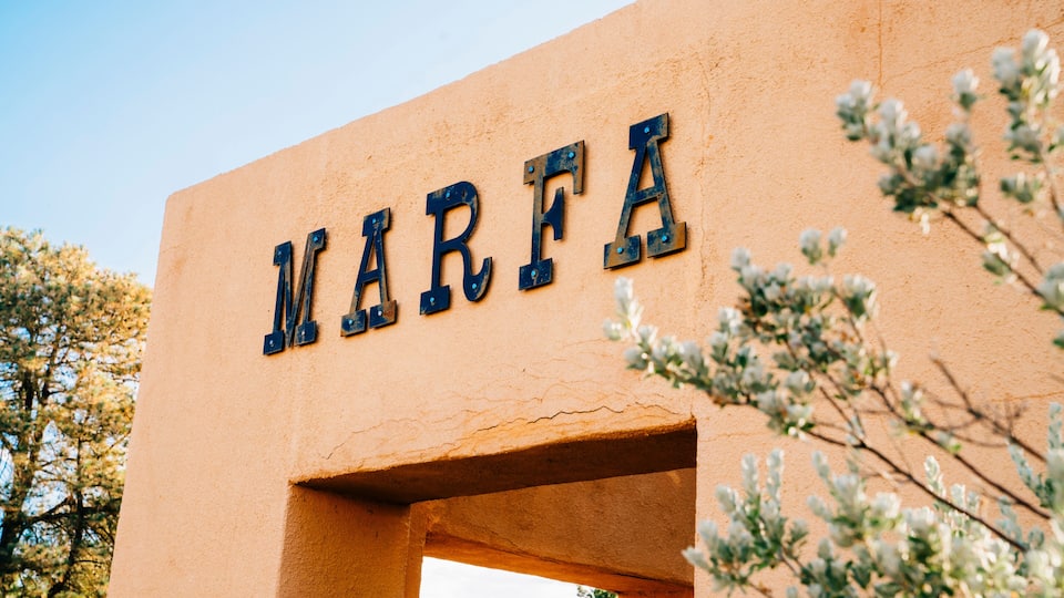 A building with the word 'MARFA' in large letters, a clear sky, and some trees in the background.