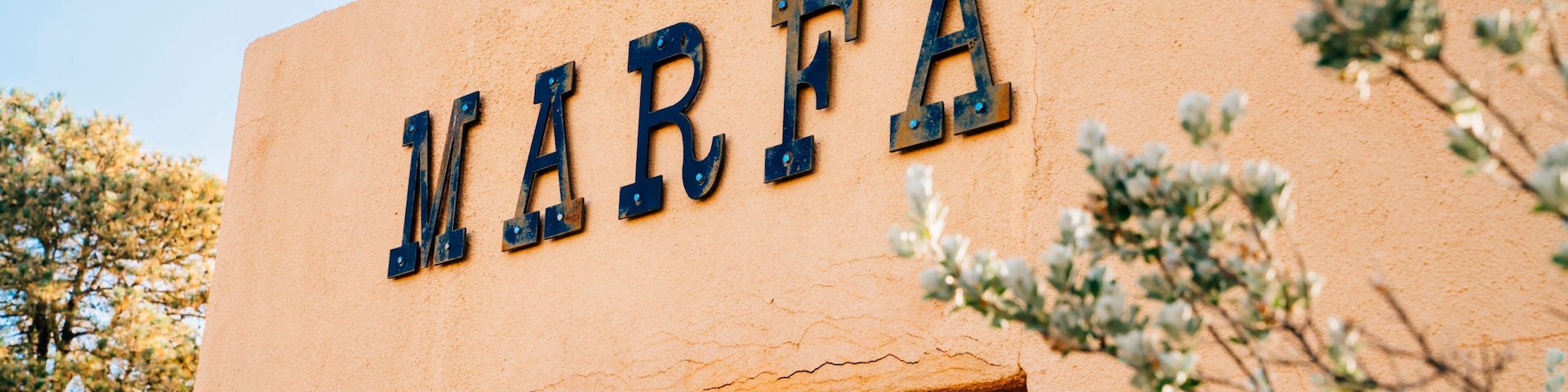 Sign for Marfa, Texas on side of stucco wall in park