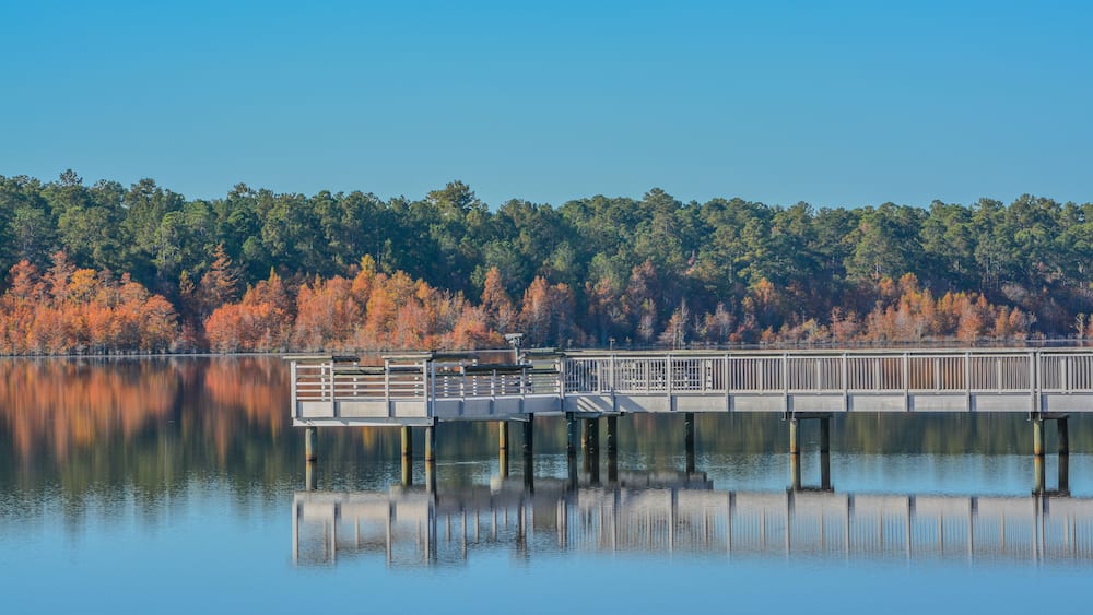 A reflection of the fishing pier and Fall leaf colors on Little Ocmulgee River in McRae, Georgia