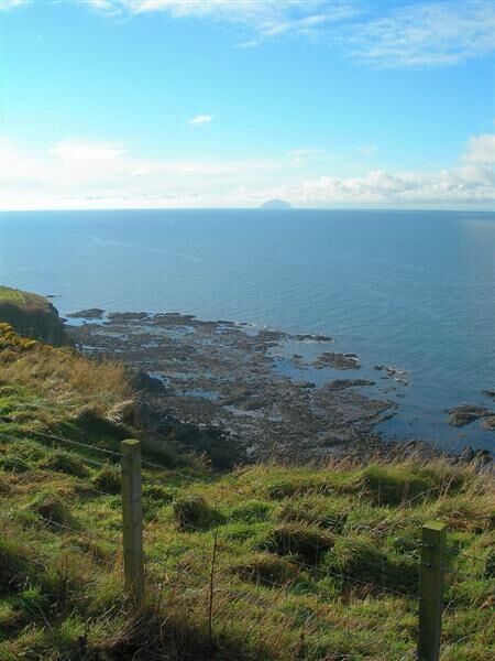 A coastal landscape with rocky shores and grassy terrain.