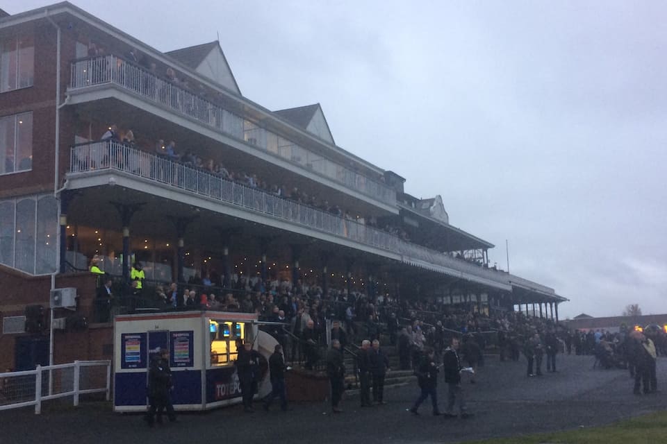 A large building with multiple balconies and a crowd of people gathered outside.