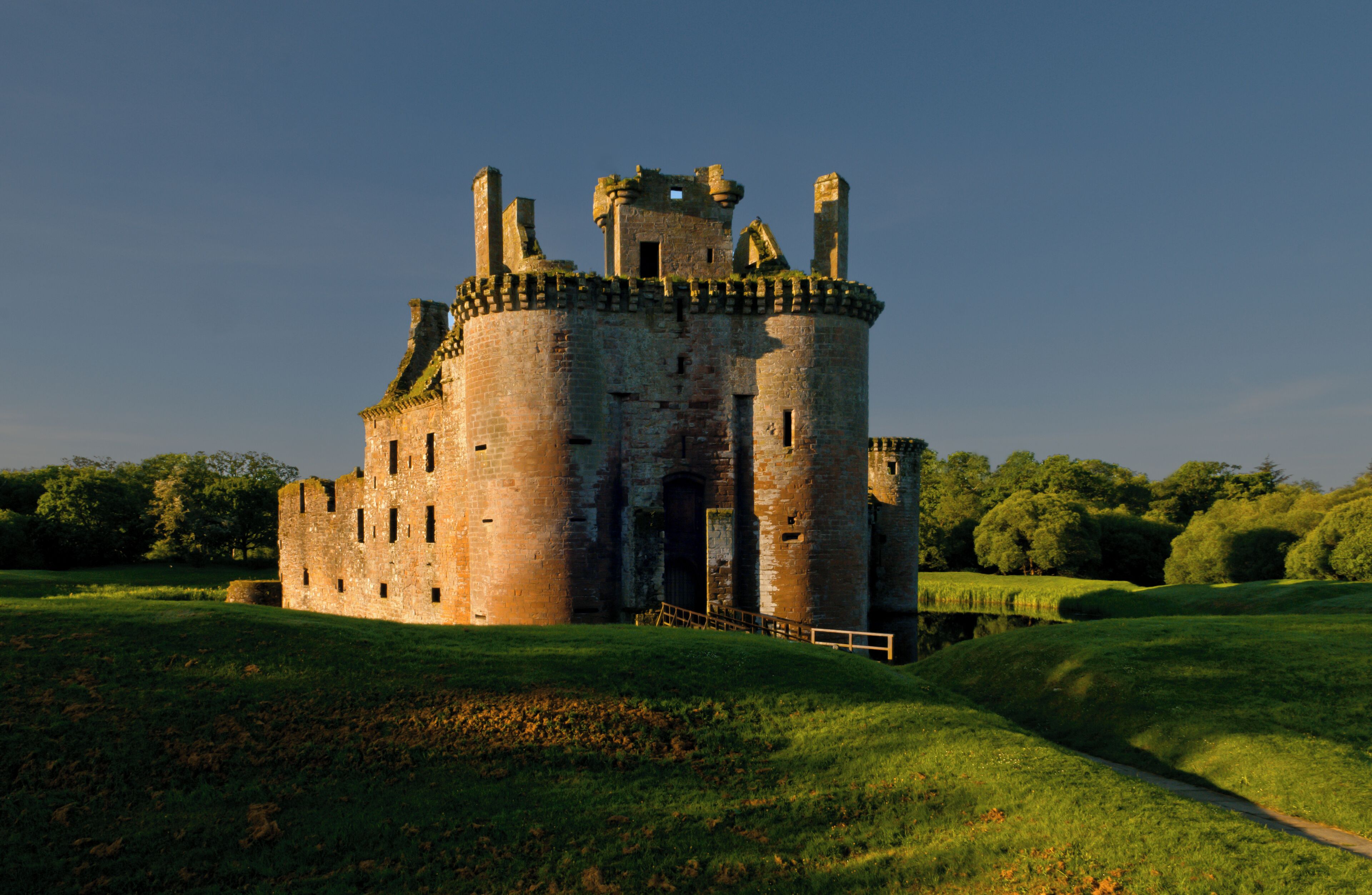A historic castle surrounded by lush green fields and trees.