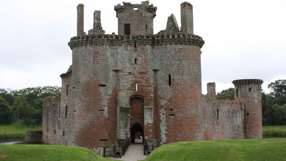 Eine historische Burg mit einem zentralen Turm, einem Rundbogenportal und umlaufenden Mauern.