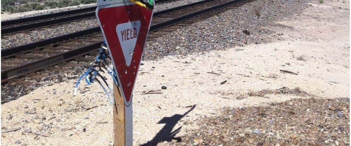A railroad crossing sign with a toy dinosaur attached to it.