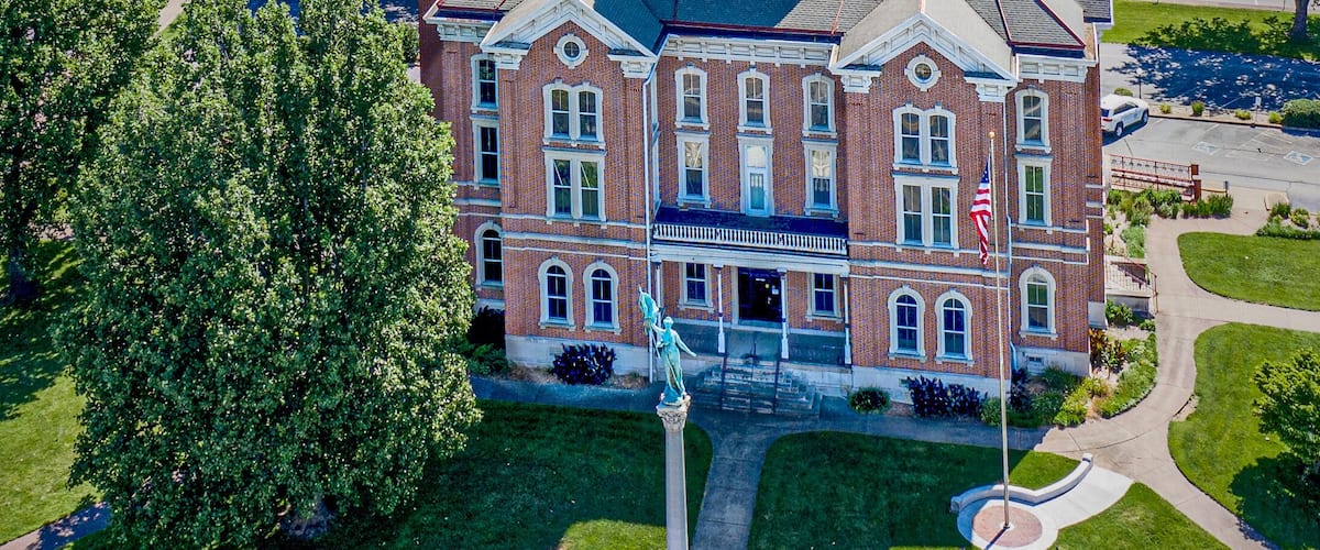 A large brick building with a dome and a statue in front.