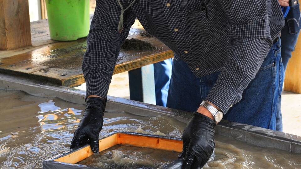 A person working with a metal frame in a muddy outdoor setting.
