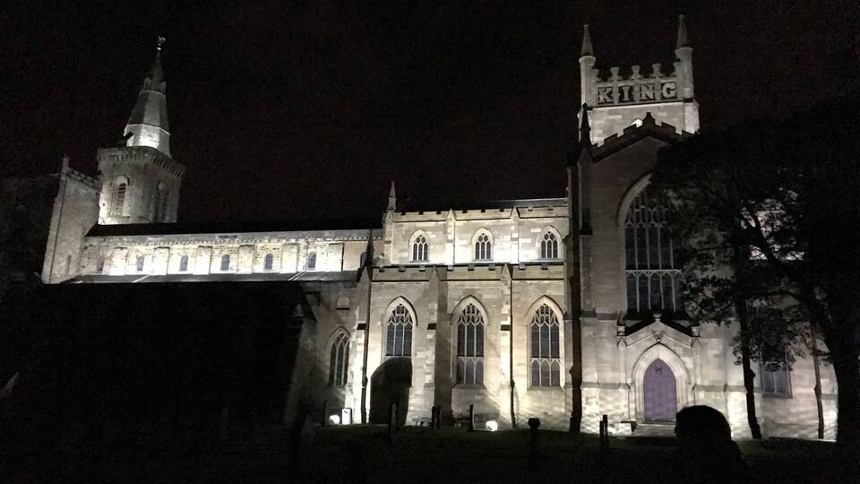 A Gothic-style church with a prominent tower and the word "KING" on its facade, illuminated at night.