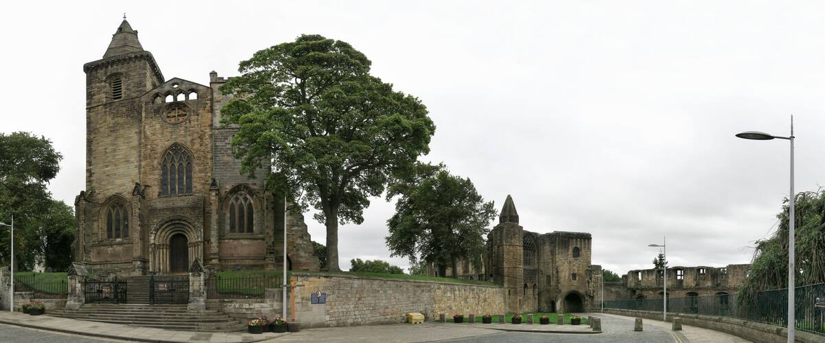 A historic stone church with a large tree in front.