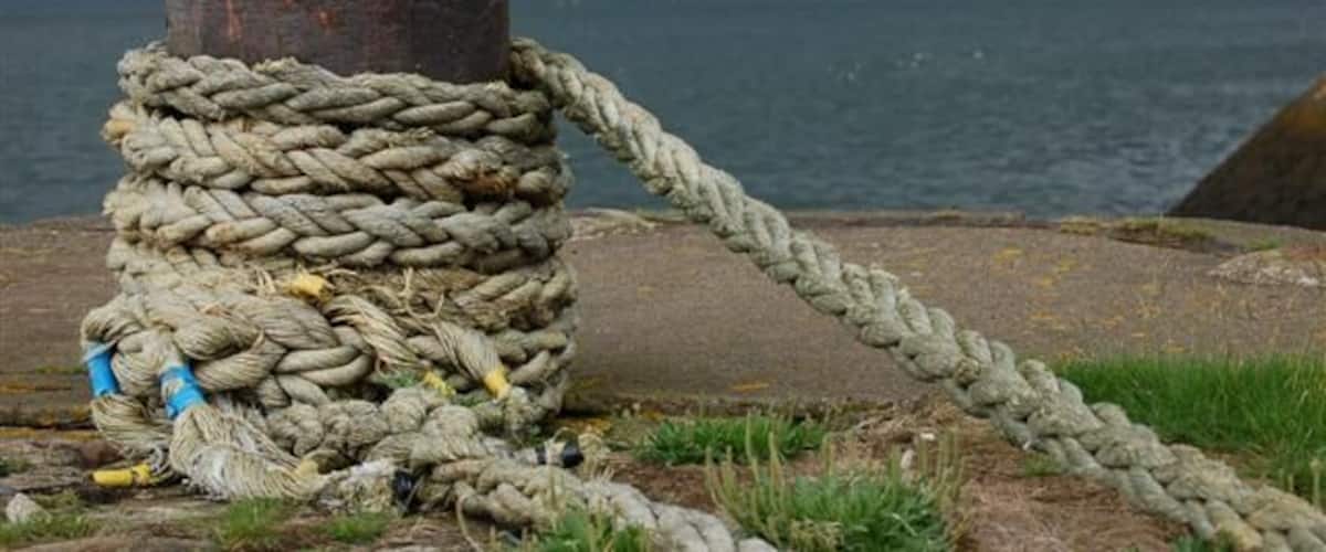 A large, coiled rope tied around a wooden post by the water.