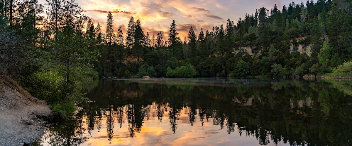A calm lake reflecting the sky and surrounding trees.
