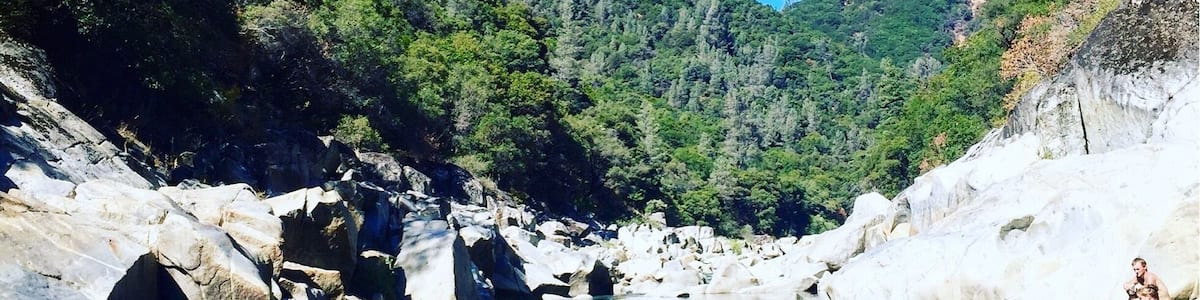 Une rivière aux eaux claires, bordée d’un paysage rocheux et d’une végétation luxuriante.