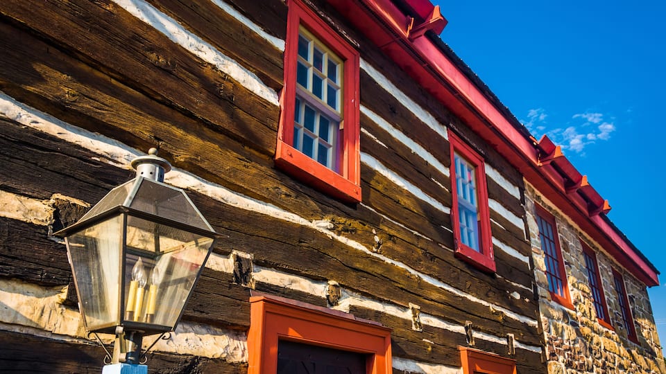 A log cabin with red trim and a lantern post.
