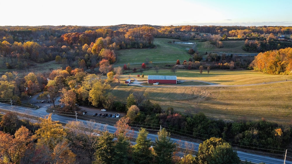 A rural landscape with autumn foliage, a barn, and a road.