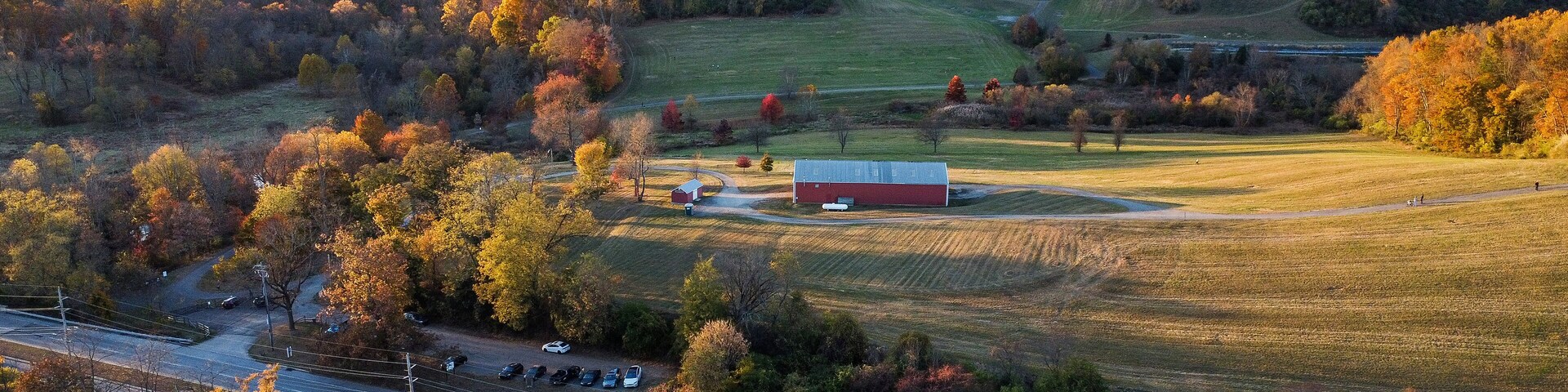 A rural landscape with autumn foliage, a barn, and a road.