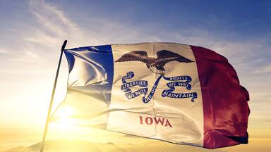 Iowa state of United States flag waving on the top sunrise mist fog