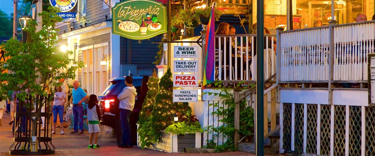 A restaurant named La Pizzeria with outdoor seating and a sign advertising beer, wine, take-out, gluten-free options, pizza, pasta, and salads.