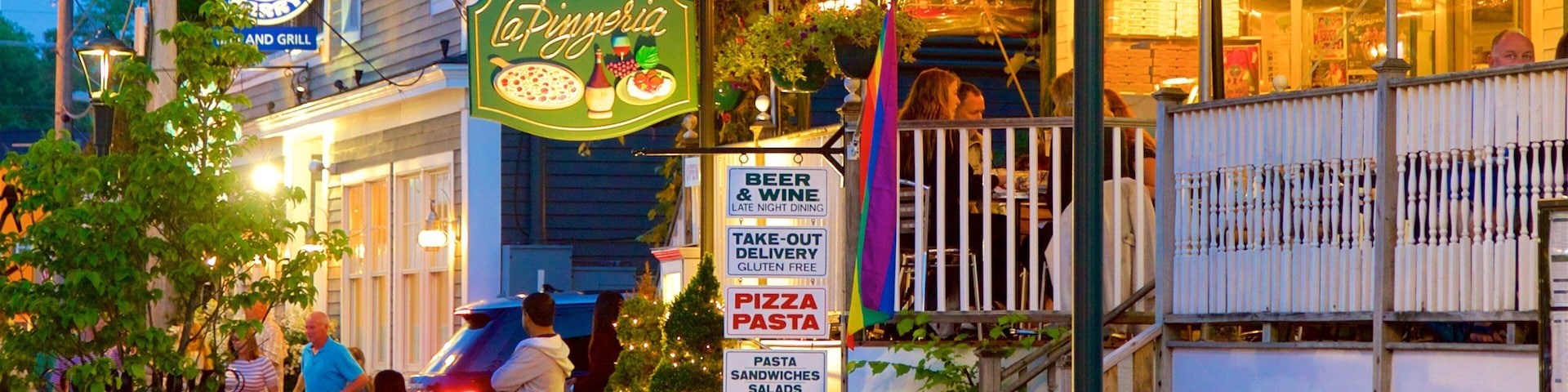 A restaurant named La Pizzeria with outdoor seating and a sign advertising beer, wine, take-out, gluten-free options, pizza, pasta, and salads.